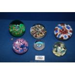 A quantity of six paperweights including red, blue, and white flowers, blue and pink swirl,