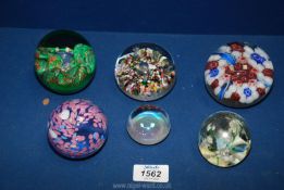 A quantity of six paperweights including red, blue, and white flowers, blue and pink swirl,
