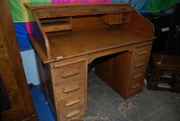 A mid Oak double pedestal scrolling roll-top Desk, the interior with pigeon holes and a drawer,