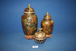 Two lidded cloisonné jars in green and gold on wooden stands,