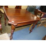 A Walnut Dining Table having shaped corners and standing on turned legs,
