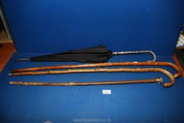Two wooden walking canes, a dented metal knop walking stick and a white metal handled umbrella.