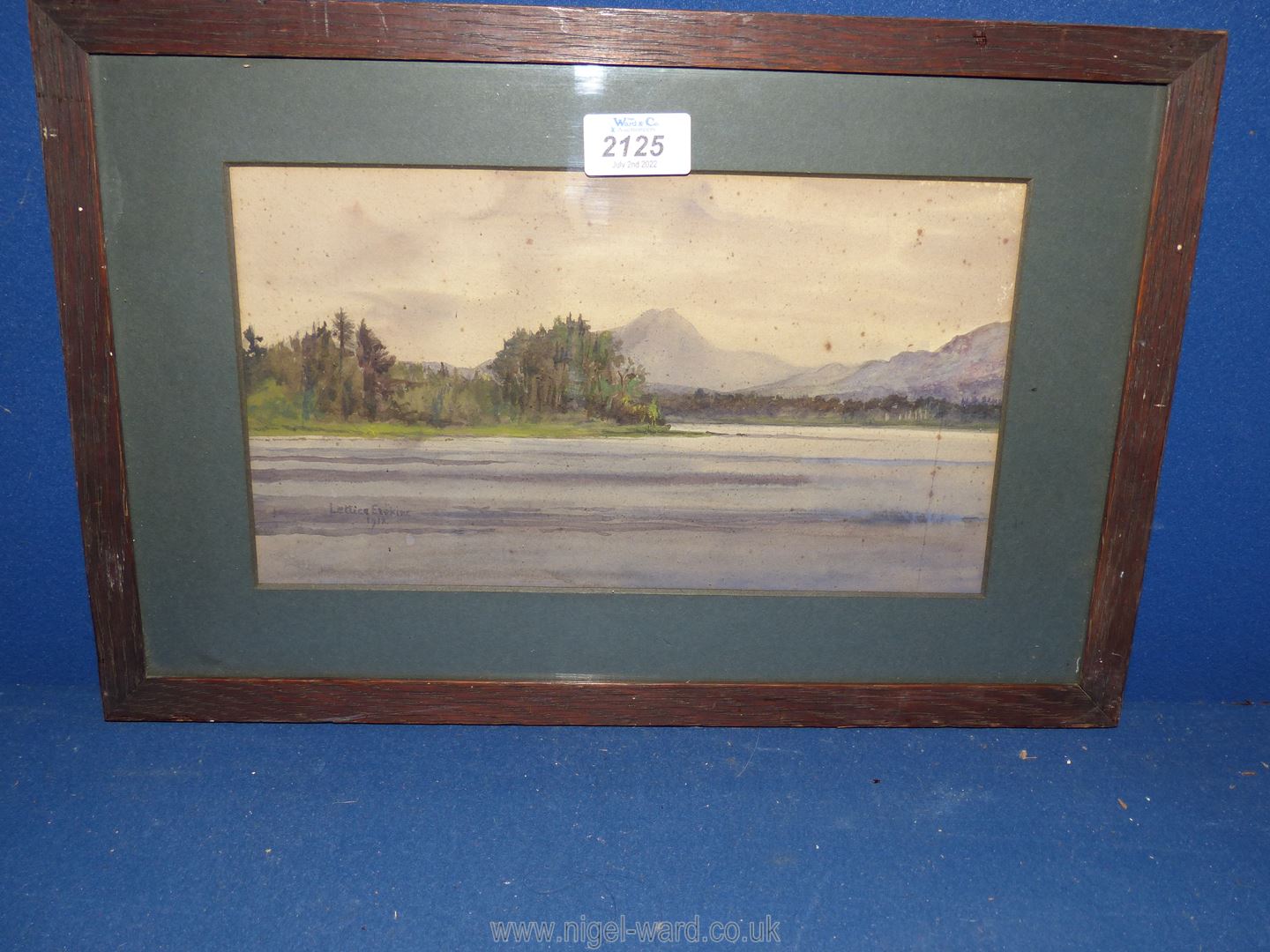 A wooden framed and mounted watercolour depicting a river scene with wooded glade and steep