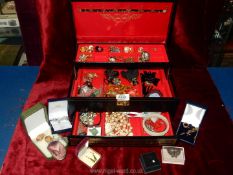 A black jewellery box containing clip on earrings, necklaces, jade and gold coloured earrings,