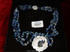 A triple strand necklace of Lapis Lazuli stones with mother of pearl floral pendant and fastenings.