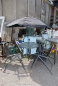 A glass topped garden patio set with 4 chairs and parasol, table 31'' diameter x 28'' high.