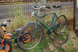 A green 'Raleigh' bike with chain guard and light.