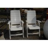 A pair of white plastic folding chairs.