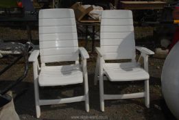 A pair of white plastic folding chairs.