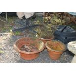 Three terracotta planters, two having ribbon design.