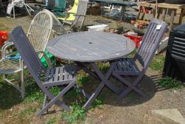 A circular teak garden table with two folding chairs,