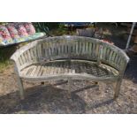 A curved back wooden garden bench in need of attention 63" wide x 33 1/2" high x 21" deep.