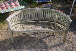 A curved back wooden garden bench in need of attention 63" wide x 33 1/2" high x 21" deep.