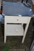 A black glass topped bedside table with one drawer, glass cracked.