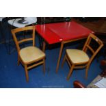 A red formica kitchen table and 2 yellow seated chairs 47" long x 24" wide x 30" high.