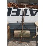 A vintage stone garden roller and garden rake.