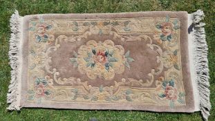 A faded lilac ground Chinese rug with cut decoration of central medallion and floral border, a/f.