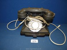 A black Bakelite dial telephone.