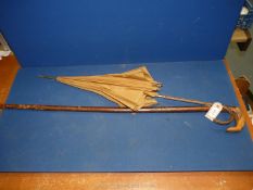 A walking stick and a gold coloured fabric parasol with snake skin handle