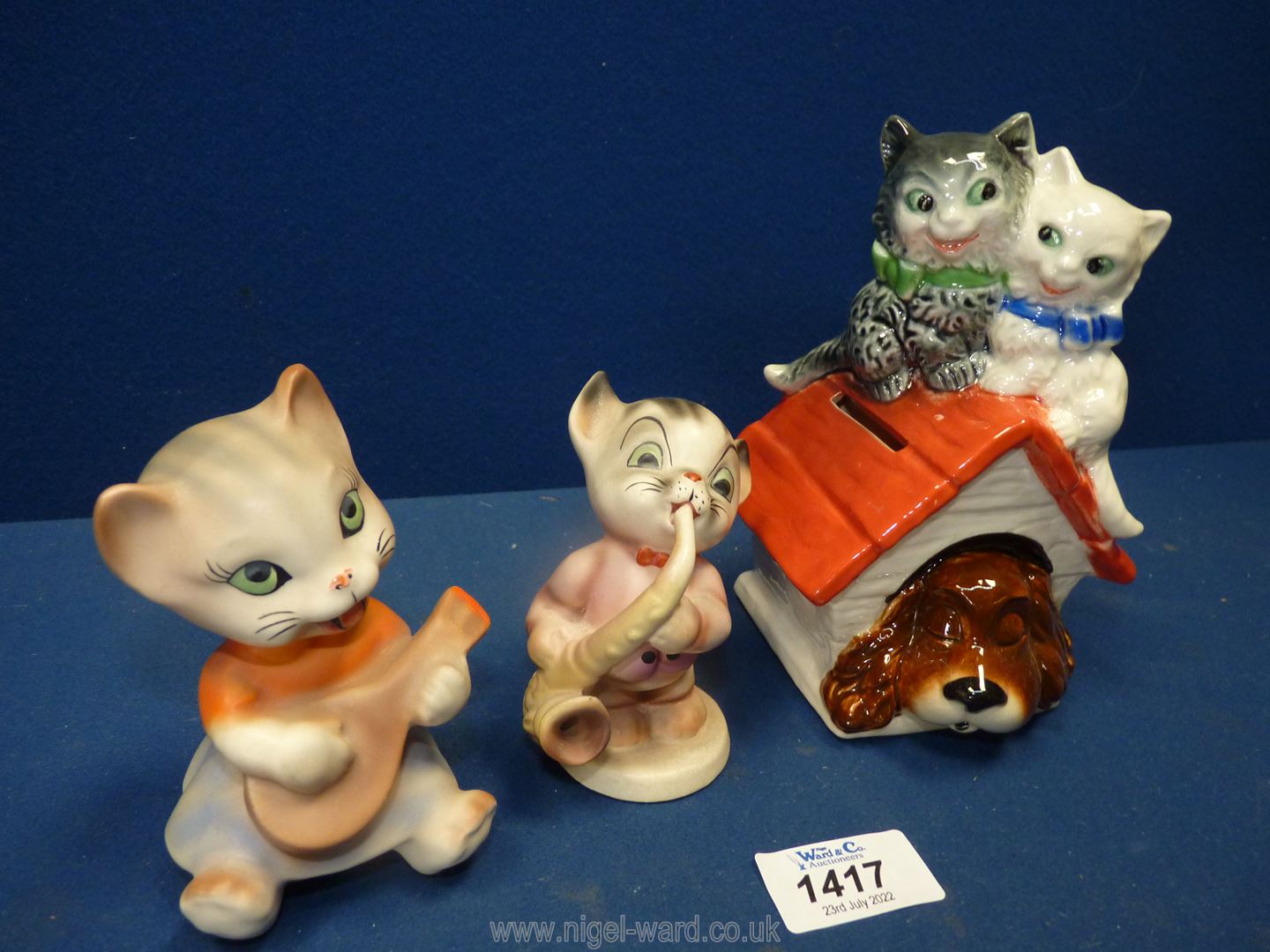 A Goebel Money box in the shape of a sleeping dog in his kennel with two cats on the roof together