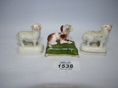 A pair of Staffordshire miniature sheep and a Staffordshire miniature reclining dog on green base,