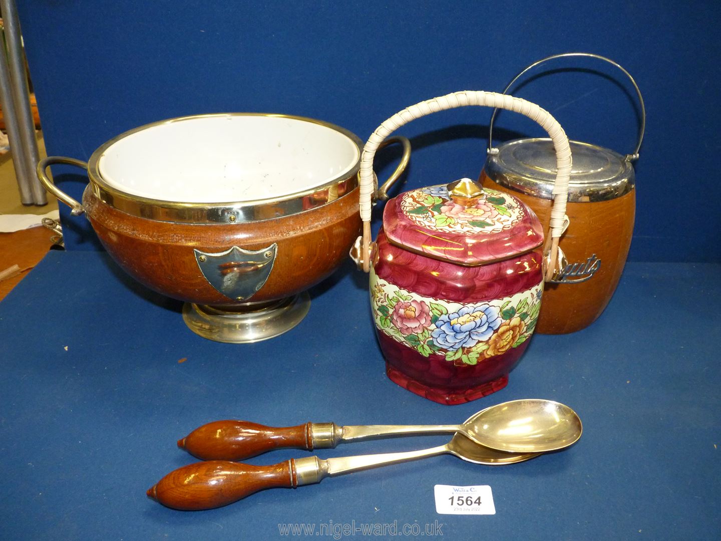 A wooden salad bowl with a china inset having two salad servers,