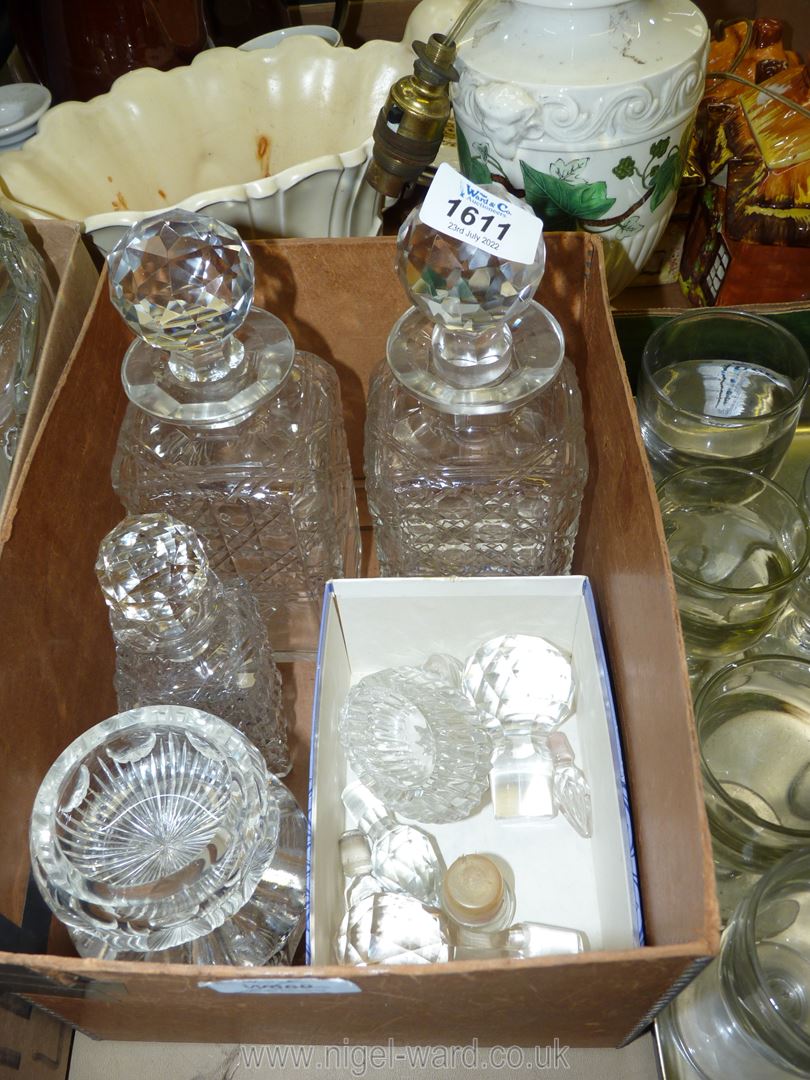 Two square glass decanters with stoppers, miscellaneous spare stoppers, and four small glass salts.