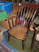An Elm seated Windsor Armchair having lathback, turned legs, stretchers and arm supports.