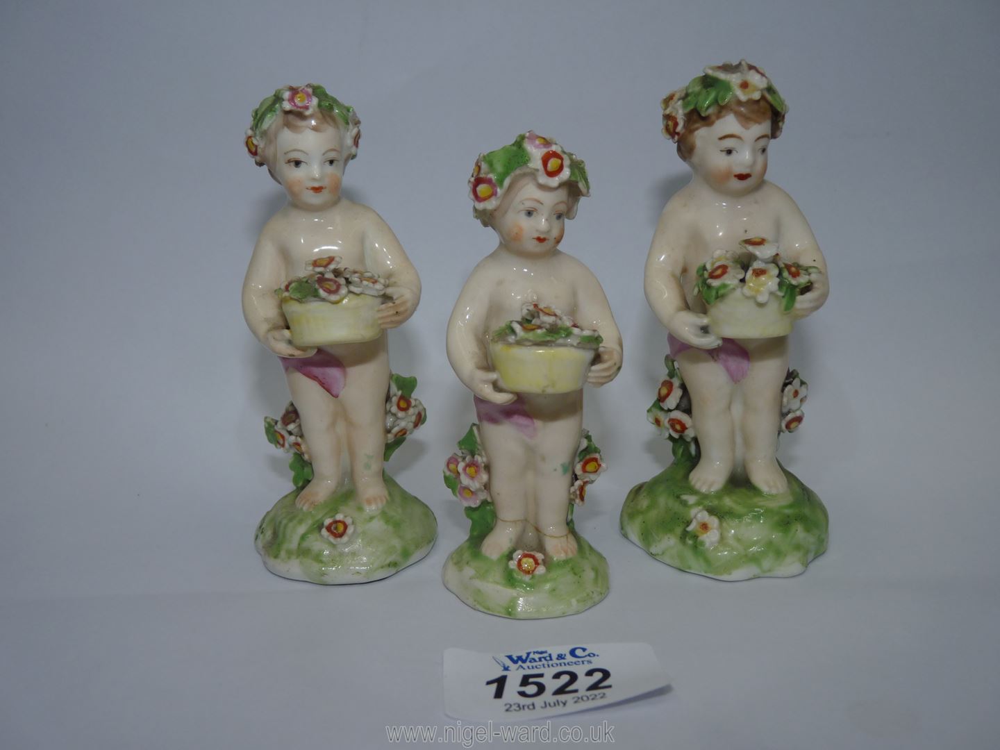 Three Derby porcelain Putti holding flower baskets, some damage, 4'' and 3 1/2'' tall.