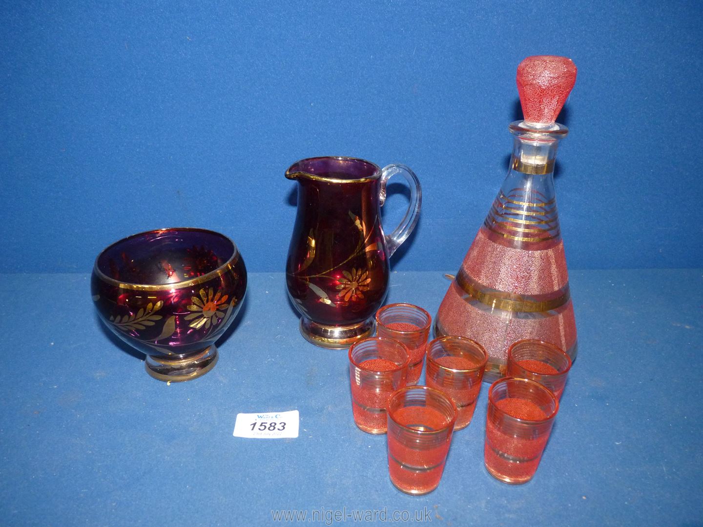 A pretty pink/gold decanter and 6 shot glasses, together with a glass lustre jug and sugar bowl.