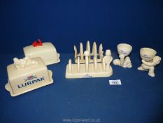 A Lurpak butter dish and toast rack and an Anchor butter dish and toast rack plus two egg cups .