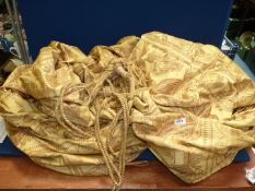 A pair of gold coloured curtains with classical scenes, lined with tie backs,
