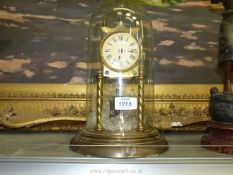 A brass anniversary Clock having Roman numerals, under a glass dome and with key and pendulum.