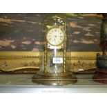A brass anniversary Clock having Roman numerals, under a glass dome and with key and pendulum.