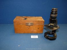 A small black microscope in wooden case.