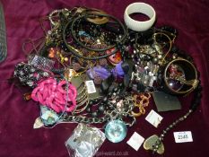 A grey basket of costume jewellery including bangles, earrings etc.