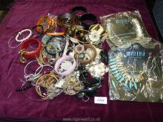 A white basket of costume jewellery including bangles, shells etc.