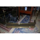 A Brass fire Kerb with slot-in iron stand, ornate cut detail to front standing on ball feet,