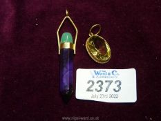 An oval topaz pendant on 9ct gold mounting and a polished stone pencil shaped pendant on yellow