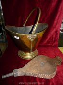 A brass coal bucket and a pair of bellows.