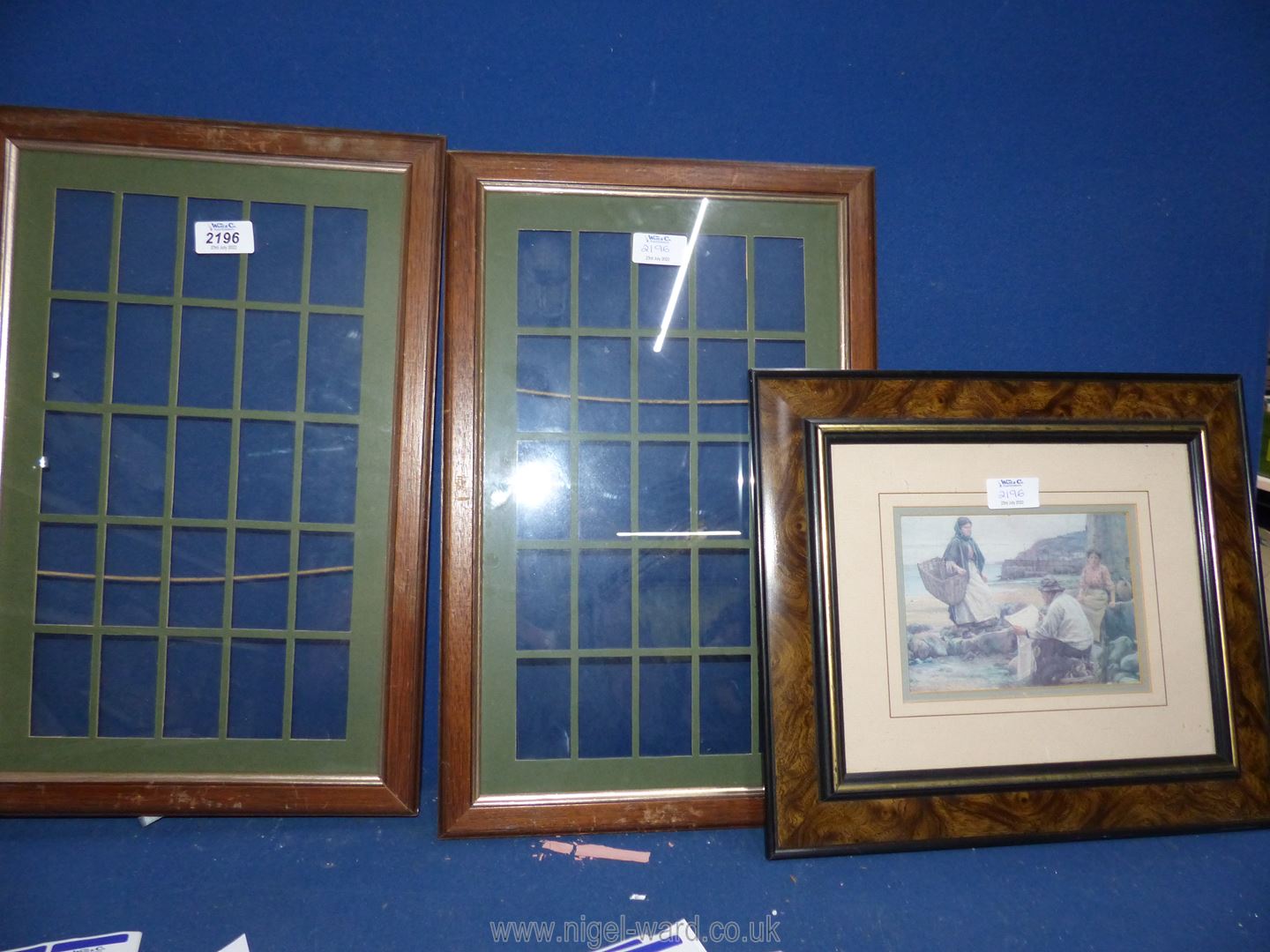 Two empty frames for cigarette card displays and a framed print of Figures in a harbour.