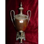 An urn shaped copper Samovar with thin handles, lid and tap on a four footed stand.