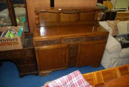 An Oak buffet sideboard with carved detail and shelf to the upstand.