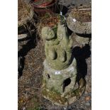 A concrete garden fountain in the form of a child with fish on base, 34" tall.