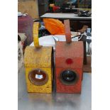 Two vintage metal railway lamps, one red and the other orange.
