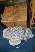 A wicker hamper of miscellaneous linen.