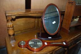 A small banjo style barometer and an oval dressing table mirror.