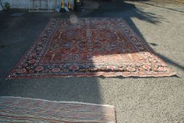 A large red, blue & green floral border pattern rug, 155" x 112" (worn).