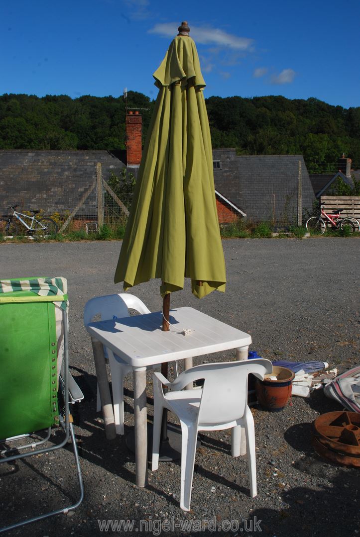 A plastic patio table, 2 chairs and a parasol.