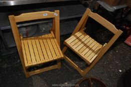 A pair of ash wood folding chairs.